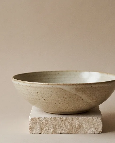 Wide shallow serving bowl in an oatmeal glaze on a stone plinth