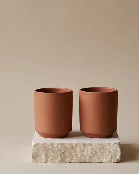 Pair of unglazed terracotta cups on a stone plinth
