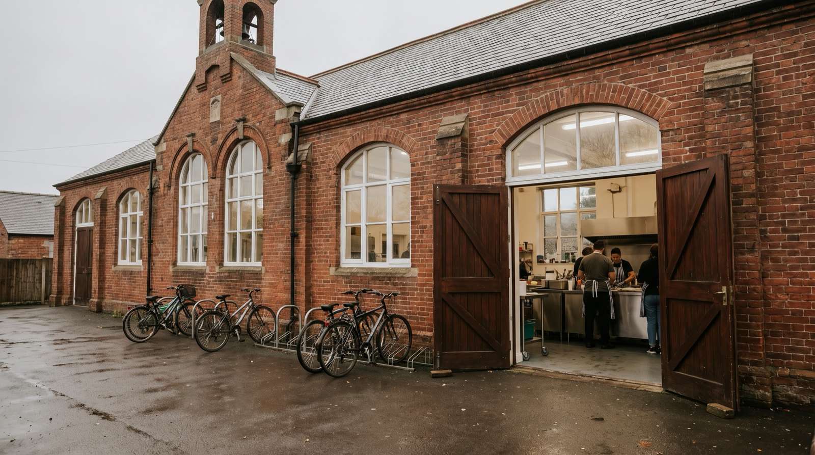 A red-brick former school with open doors and bikes outside