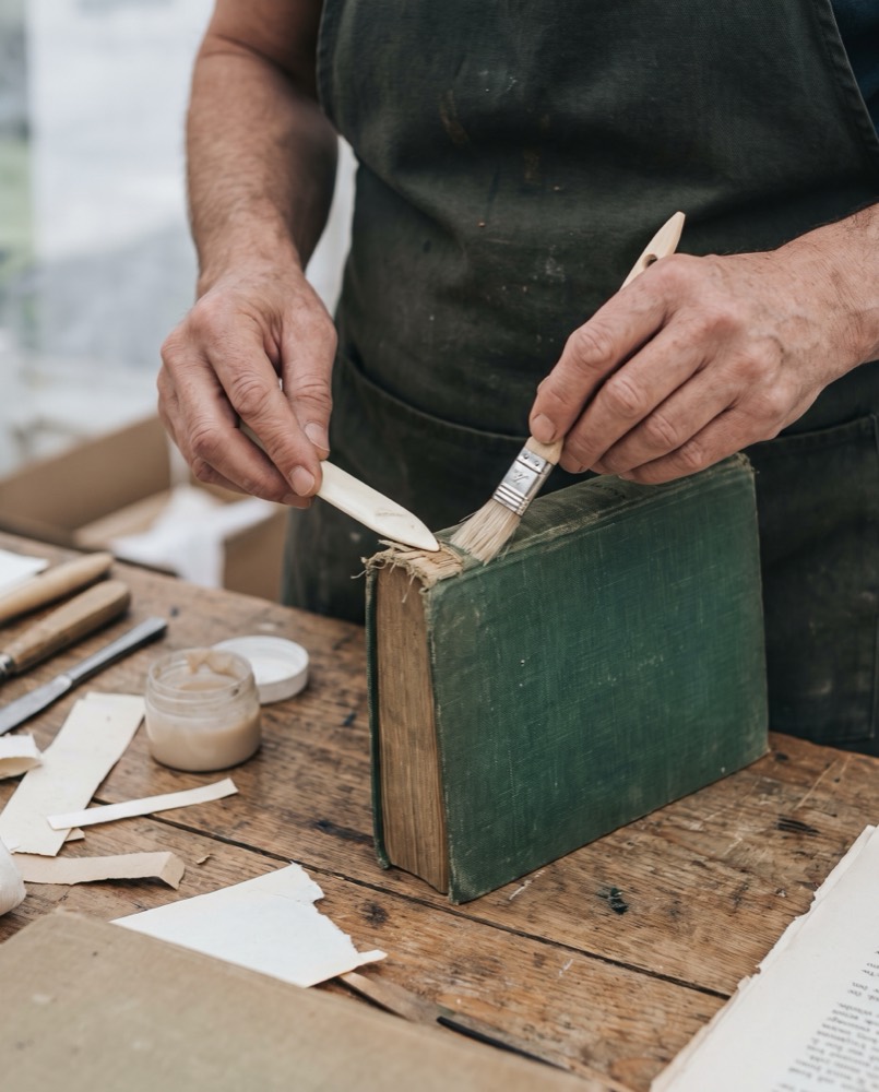 Hands repairing a cloth-bound book