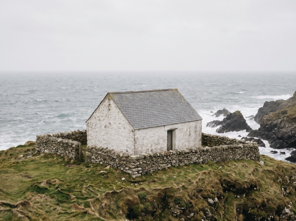 A small whitewashed stone library on a rocky headland